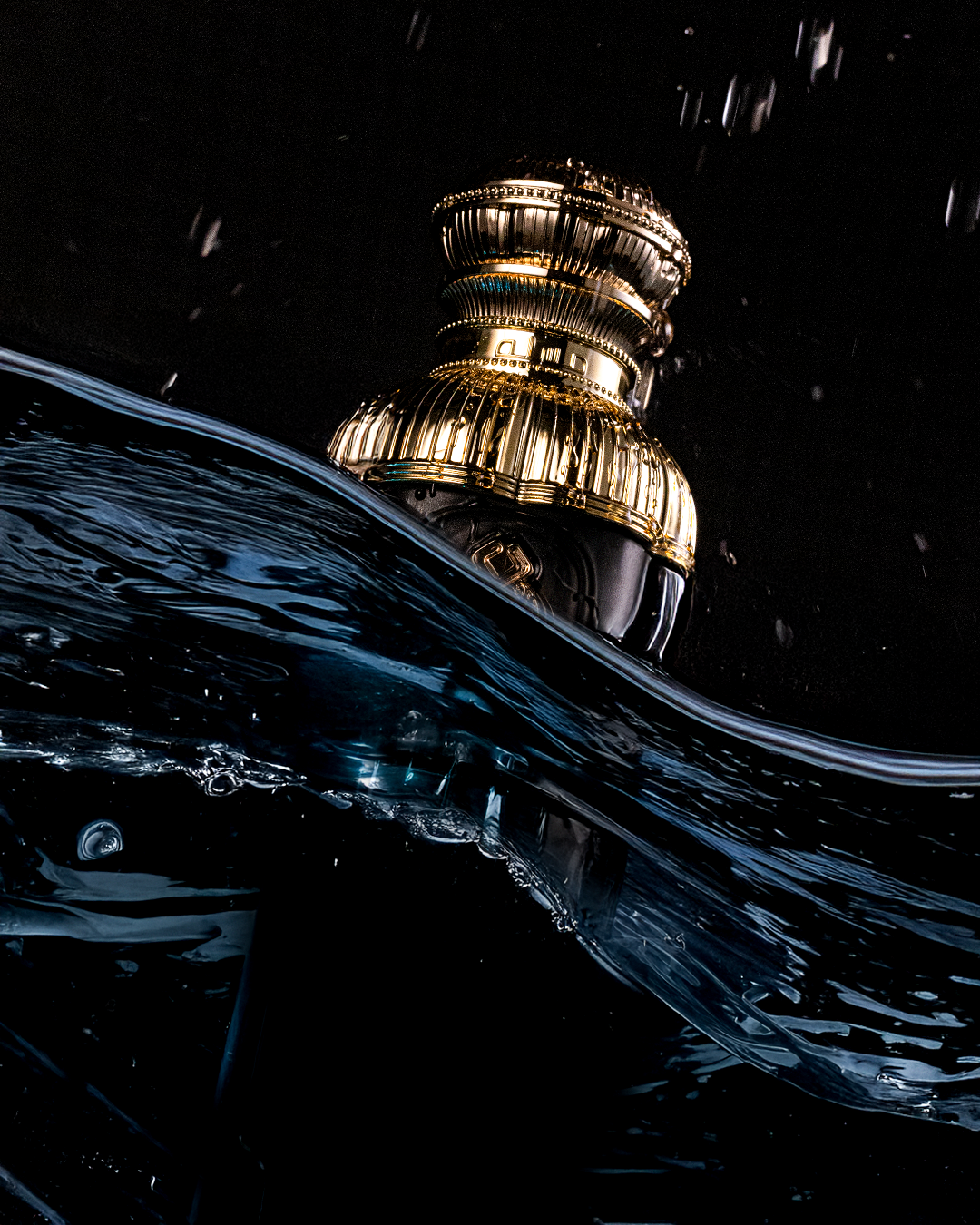 Masala perfume campaign: a gold-capped bottle emerging from dark blue water